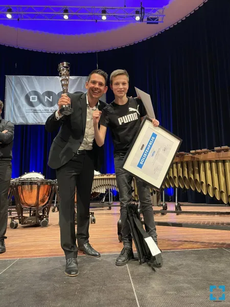 Dirigent Guido Pouwels en jongste lid van de Percussiegroep Siem Corsten nemen de prijs in ontvangst. Tevens ging de solistenprijs voor beste paukenist naar Leveroy. 