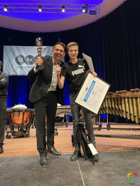 Dirigent Guido Pouwels en jongste lid van de Percussiegroep Siem Corsten nemen de prijs in ontvangst. Tevens ging de solistenprijs voor beste paukenist naar Leveroy. 